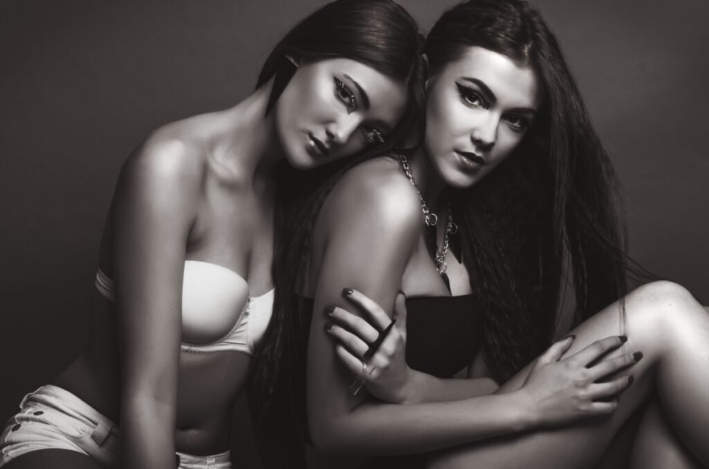 Artistic black and white photo of two women posing in lingerie during a photoshoot.
